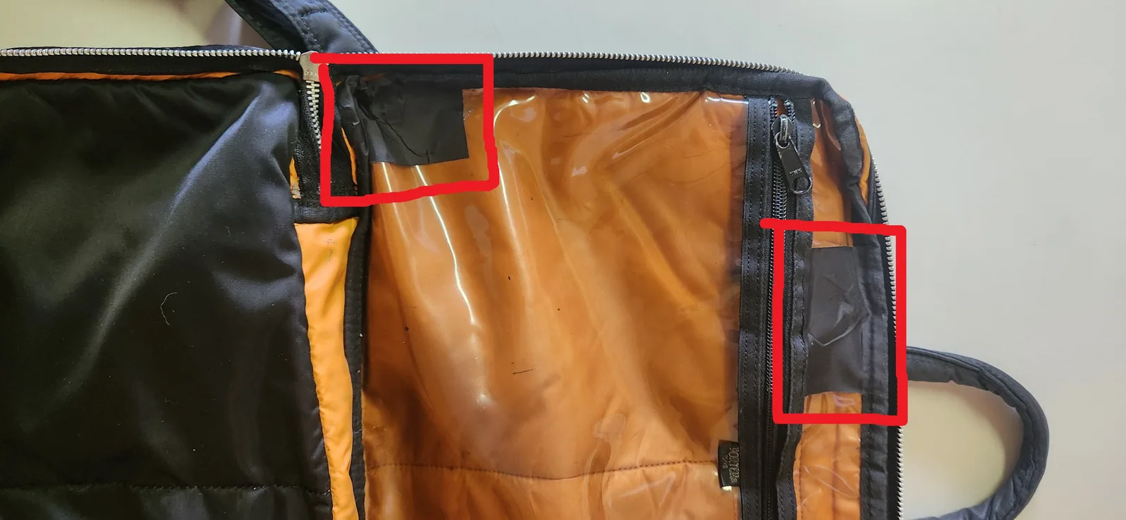 内部の透明プラスチック間仕切りにできたひび割れを、補修シートで直した2箇所（赤枠）